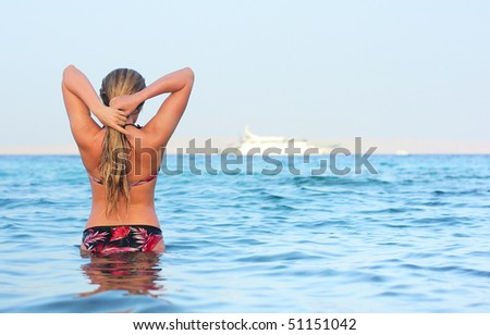 Alone woman standing in sea water and looking to horizon
