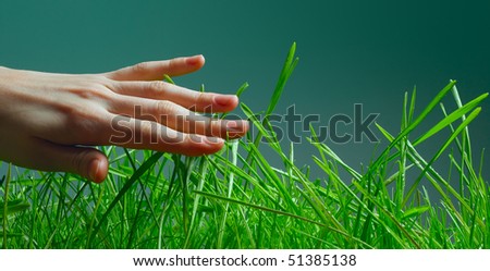 Hand over green wet grass over dark background