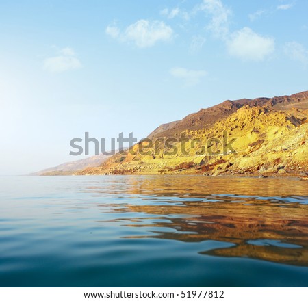 Sea with waves and mountain under sunset light