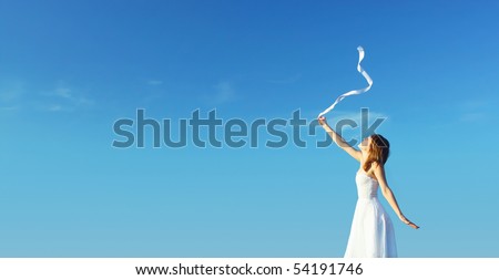 Young woman in white dress with white ribbon over clear blue sky background