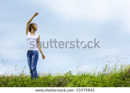 Alone woman with thin ribbon standing on meadow with grass over sky background