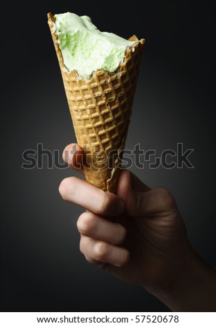 Ice cream cone in hand over black background