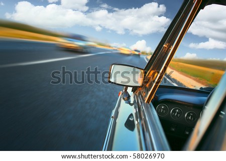 Car with mirror and dashboard on blurred asphalt road with another cars