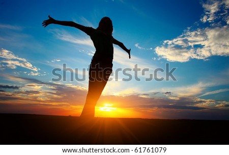 Young woman with raised hands standing on land over sunset light