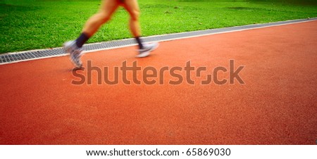 Motion blurred sportsmen running on red stadium\'s track