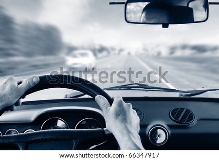 Driver\'s hands on steering wheel inside of a car