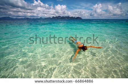 Young woman with a mask snorkeling in clear sea