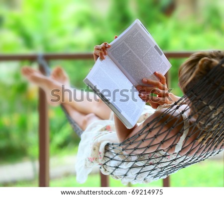 Young woman reading a book lying in hammock