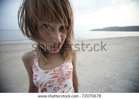 Young woman with fluffy hair puckering her face. Wide angle lens distortion. Focus on lips