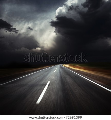 Blurred asphalt road and dark thunder clouds over it