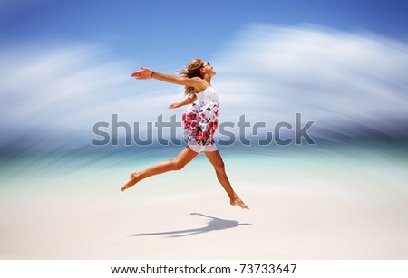 Young woman in summer dress jumping on sand. Motion blurred background