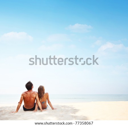 Young man and woman sitting on warm sand by a sea and looking to somewhere Young man and woman sitting on warm sand by a sea and looking to somewhere