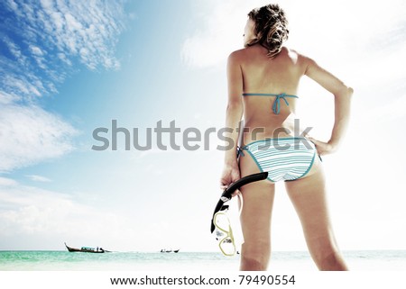 Young woman standing with mask and snorkel by blue sea and going to swim