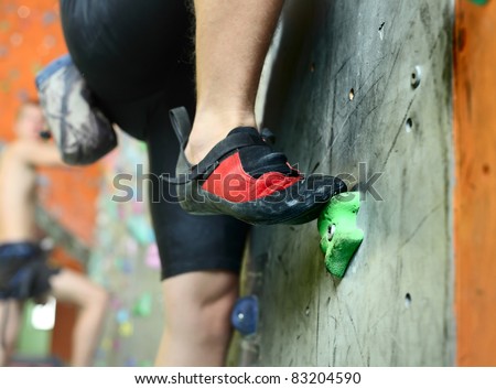 Young man\'s foot climbing indoor wall