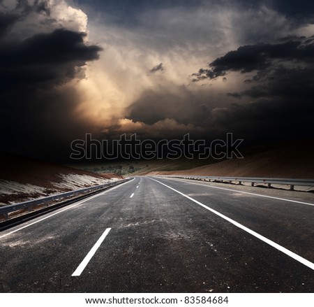 Dirty asphalt road and dark thunder clouds