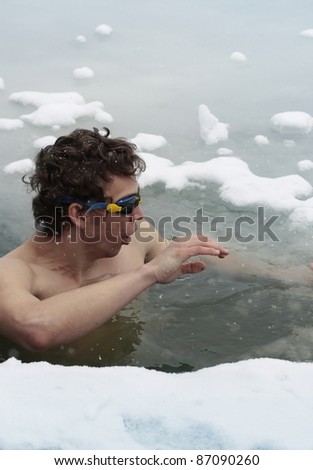Young man having recreation swim in an ice hole
