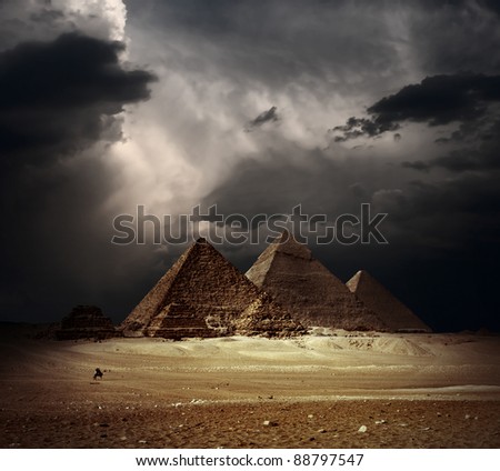 Great pyramids in Giza valley with dark clouds on the background