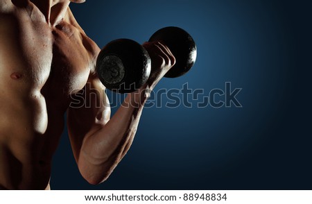 Part of a man\'s body with metal dumbbell on a blue background