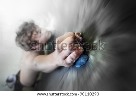 Young man climbing indoor wall. Focus on a fingers. Motion blurred wall around hand