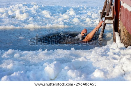 Man swimming in the ice hole at sunny day