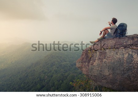 Hiker relaxing on top of the mountain and drinking bottled water
