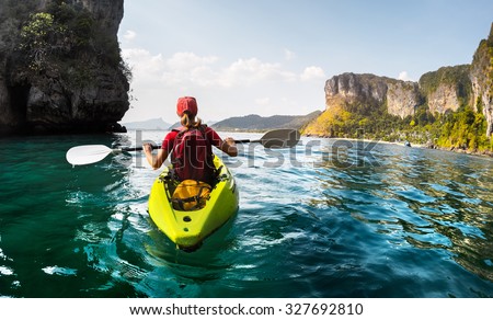 Lady paddling the kayak in the calm tropical bay