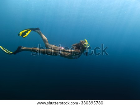 Underwater shot of the lady moving on the breath hold in the depth