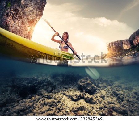 Split shot of the lady paddling the kayak in the calm tropical sea with underwater view of the bottom