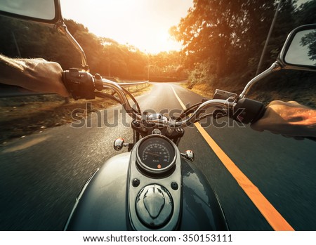 Man riding the motorcycle on the empty asphalt road through the forest