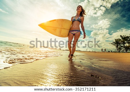 Lady walking with surfboard along the tropical beach