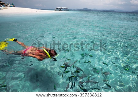 Young lady snorkeling with fish in a clear blue sea