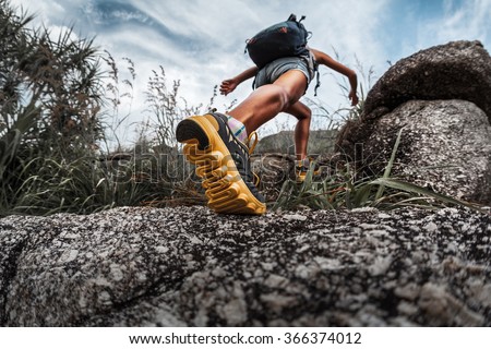 Lady hiker walking through the rocky land. Focus on the foot