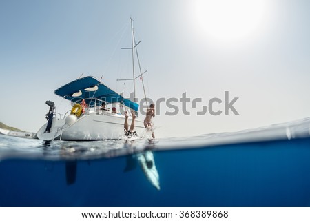 Split shot of the couple jumping into the clear sea from the sail boat