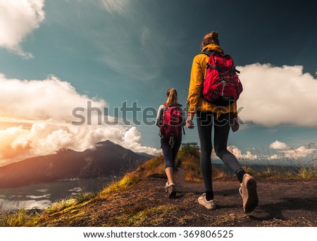 Two ladies hikers walking on the path on top of the mountain