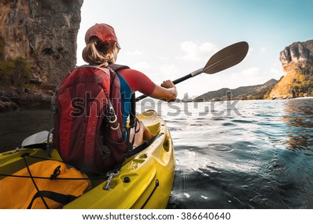 Lady paddling the kayak in the calm bay with limestone mountains
