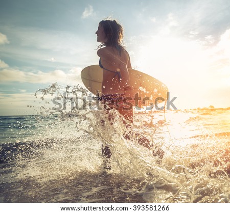Woman running into the sea with surf board