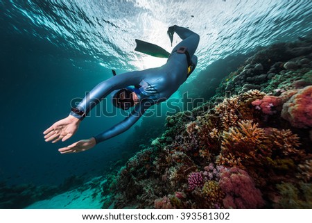Free diver swimming underwater over vivid coral reef. Red Sea, Egypt