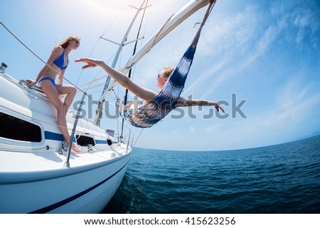 Two women relax on the sail boat moving in the sea