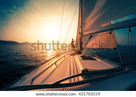 Young man on the sailing boat at sunset