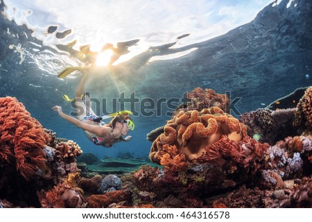 Young lady snorkeling over coral reef in the tropical sea.