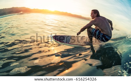 Young man surfs the ocean wave at calm sunrise