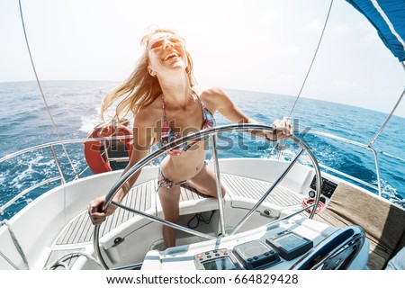 Young happy woman steering sailing boat in a tropical sea