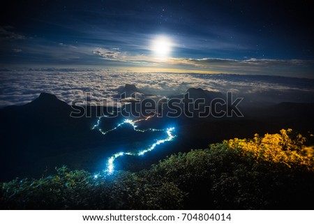 Illuminated path to the top of the mountain of Adam?? Peak with moon and stars in the sky. View from Adam?? Peak, Sri Lanka