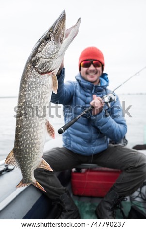Young happy angler holds pike fish