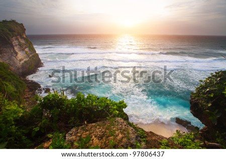 Coast of Indian ocean with waves and cloudy sunset sky. Bali, Indonesia