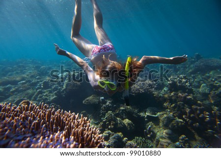 Young woman diving on a breath hold and enjoying a coral reef views in tropical clear sea
