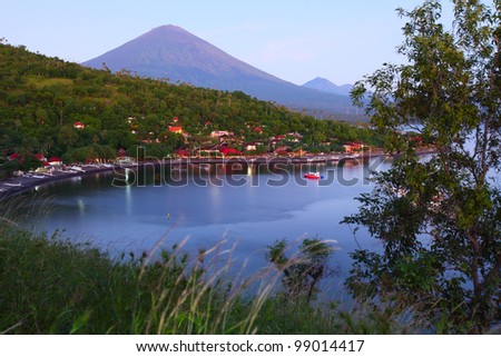 Volcano Agung (Bali island, Indonesia) lighted by rising sun and calm lagoon with sail boat