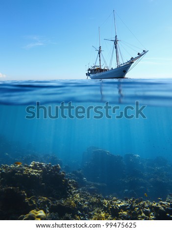 Sail boat in tropical calm sea and coral reef underwater