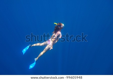Young woman diving on a breath hold and fining in blue transparent sea