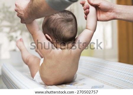 baby tries to sit down with the help of a parent charge